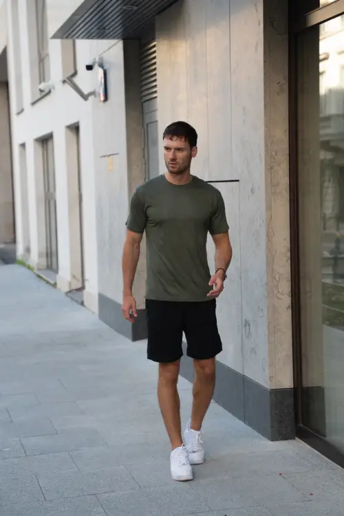 Mężczyzna w zielonym t-shircie sportowym merino podczas spaceru w mieście