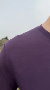 Zbliżenie na fioletowy t-shirt sportowy z wełny merino, widoczna faktura dzianiny na ramieniu